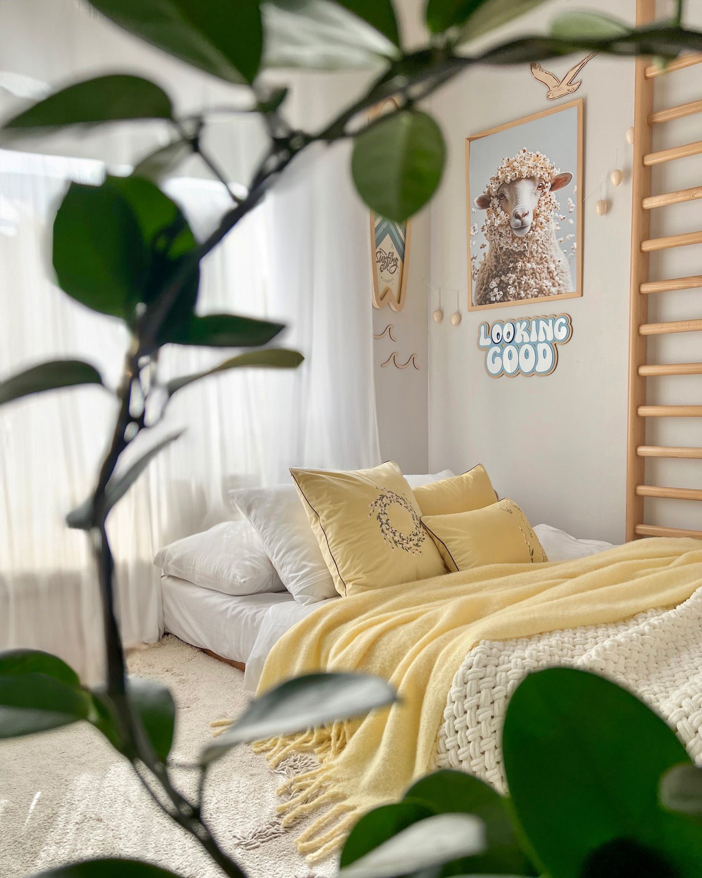 Sunlight fills a little boy’s room with yellow bedding, patterned cushions and a wooden wall ladder.