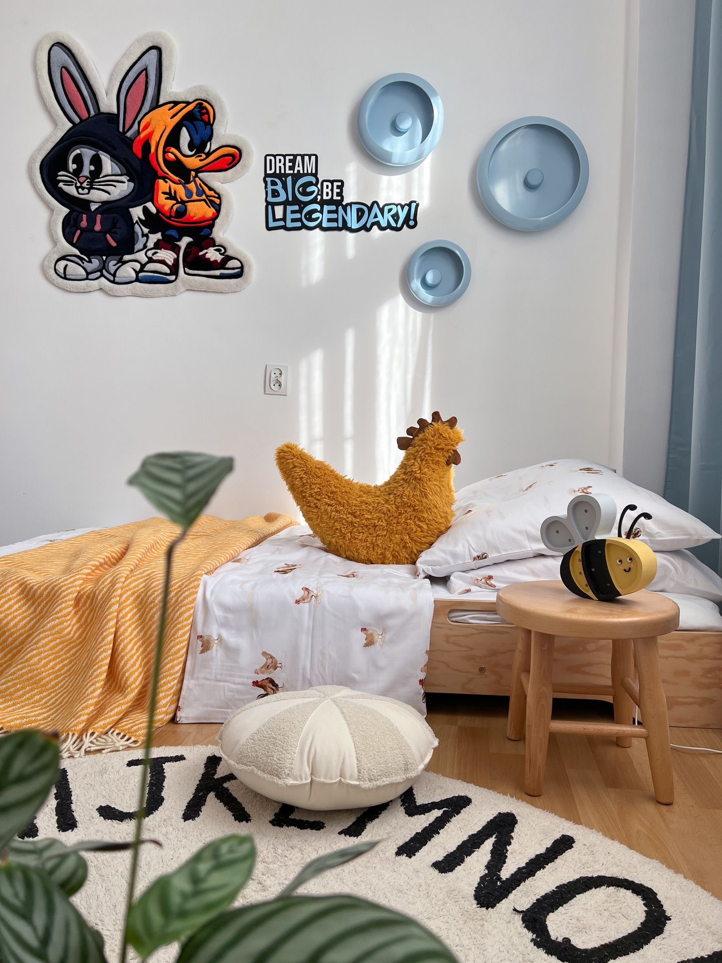 A colourful children’s room with a knitted hen, a bee and yellow bedding.