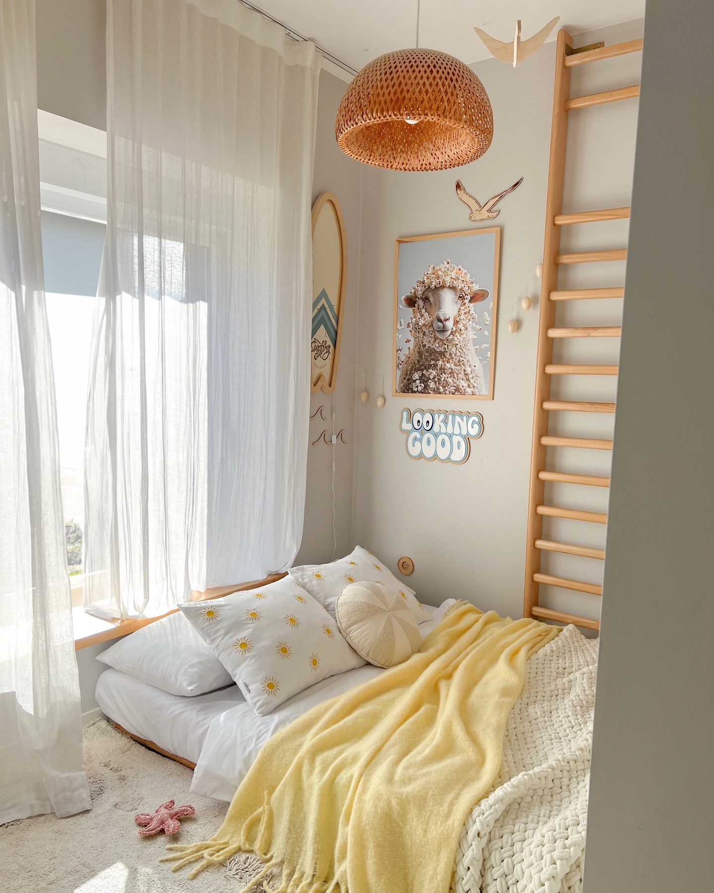 Sunshine falls across yellow bedding and a wooden wall ladder in a children’s bedroom.
